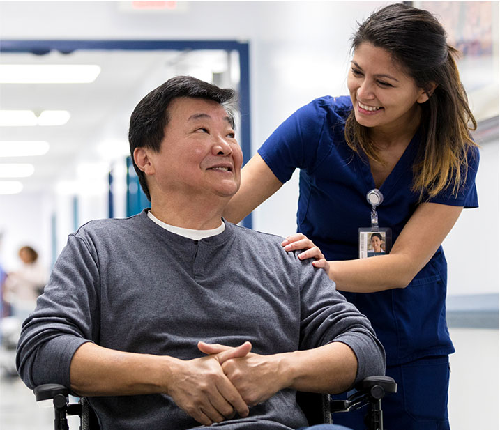 Una proveedora de atención médica ayudando a un hombre en silla de ruedas