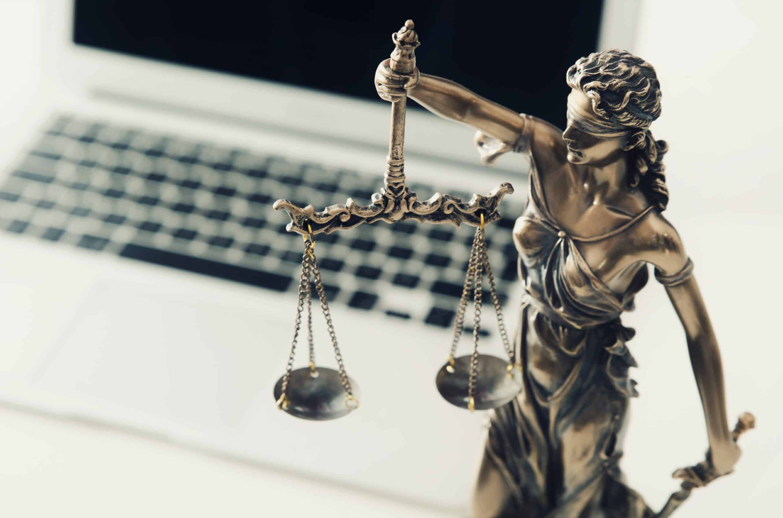 Laptop computer with scales of justice statue in front