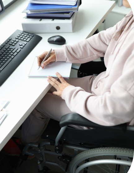 Person in a wheelchair writes a note at a work desk