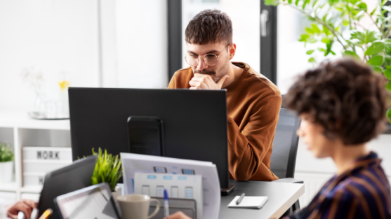 UX designer pensively looking at a screen in an office.