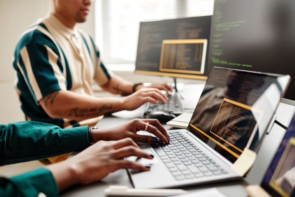 Two people working on laptops in an office.