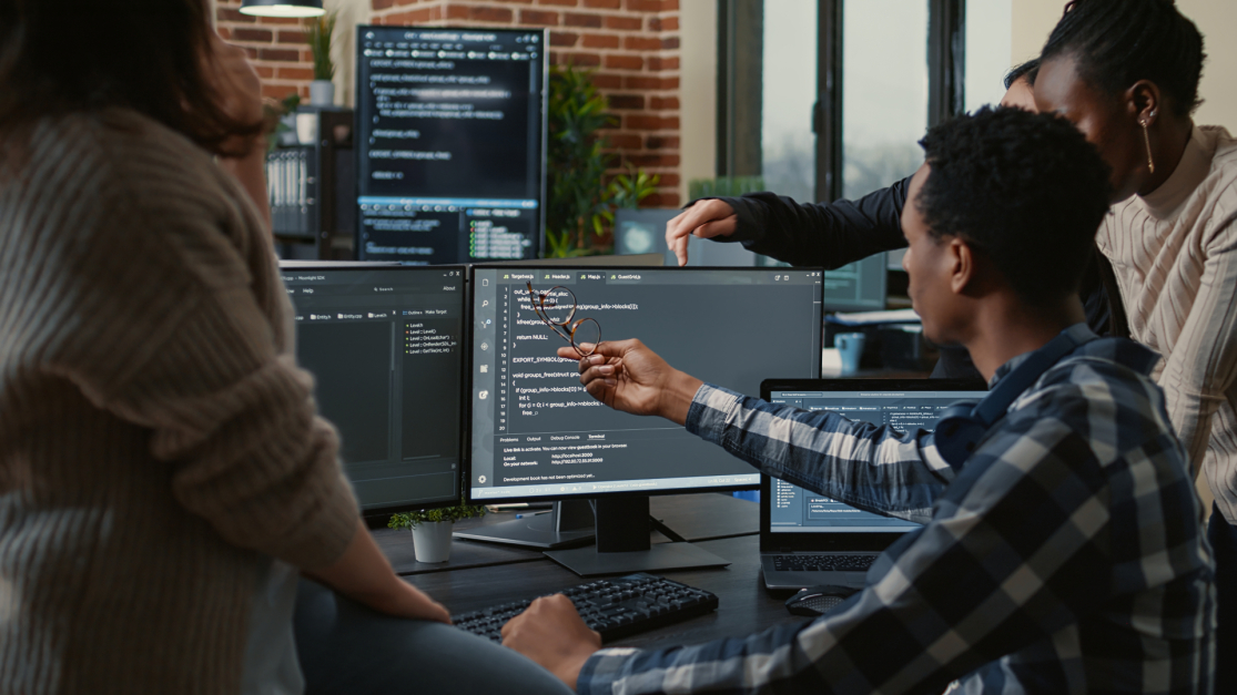 A group of coworkers collaborating on a computer project in an office.