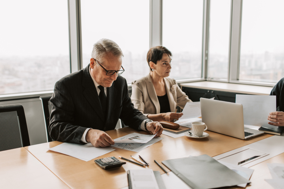 Three lawyers discussing documents at a table during a business meeting.