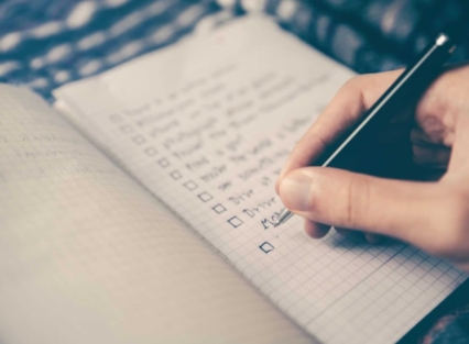 Person writing a list in book